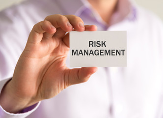 Businessman holding a card with RISK MANAGEMENT message