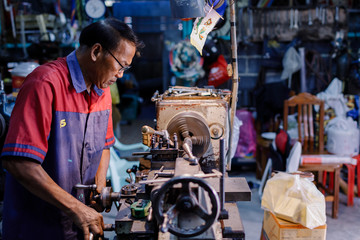 Asians Craftsman being machined steel in a factory