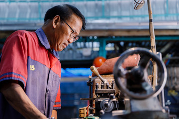 Asians Craftsman being machined steel in a factory