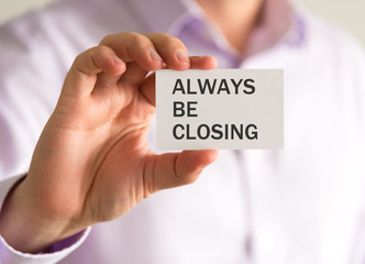 Businessman holding a card with ALWAYS BE CLOSING message
