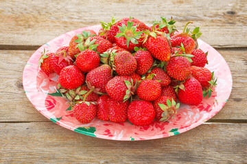 Delicious ripe strawberries on the plate, on wooden table.