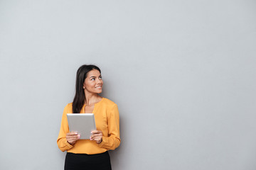 Business woman holding tablet computer and looking away
