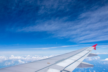 Fototapeta na wymiar Airplane wing on beautiful blue sky with clouds