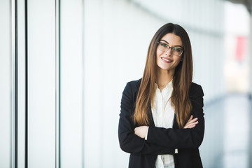 Smiling young Business woman crossed arms, standing against office