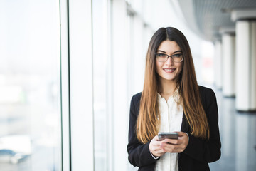 Fototapeta premium Young woman with typing on mobile phone in the office