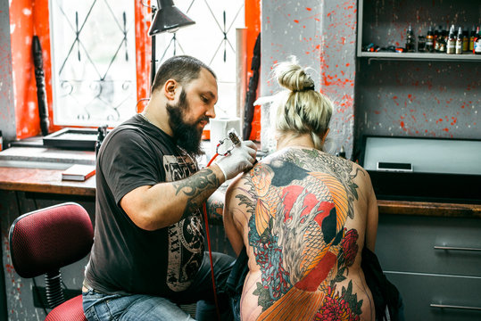 the process of creating a tattoo on the back of a girl