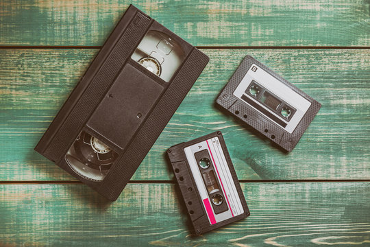 Audio and video Tape Cassettes on green wooden table. Vintage toned image