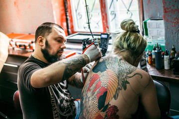 the process of creating a tattoo on the back of a girl