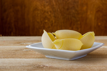 żółty makaron jajeczny muszelki na drewnianym stole © Krzysztof Matloch