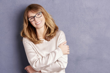 Confident woman. Shot of a beautiful mid adult woman smiling on grey background.