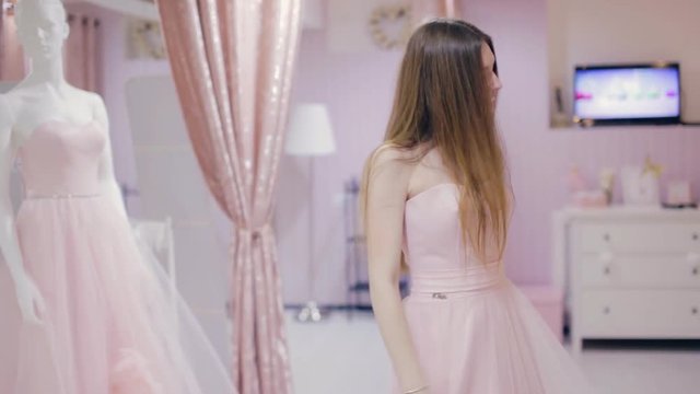 Pretty girl trying on prom gown and posing
