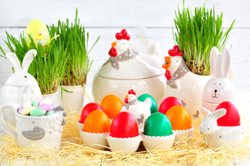 Easter eggs colored with organic paints and plate in the form of chickens and rabbits on a white wooden background.