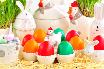 Easter eggs colored with organic paints and plate in the form of chickens and rabbits on a white wooden background.