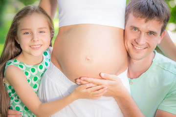 Happy family holding belly of pregnant woman