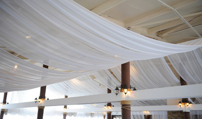 Fabric drape on the restaurant ceiling. Bright interior, lighted lantern. The decor for the wedding...