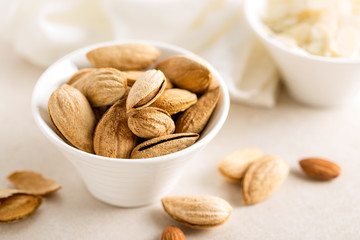 Almond nuts in a bowl on white background, healthy eating