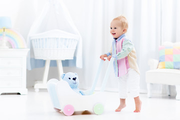 Baby with push walker in white bedroom