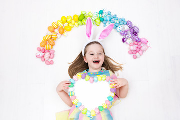 Child on Easter egg hunt. Pastel rainbow eggs.