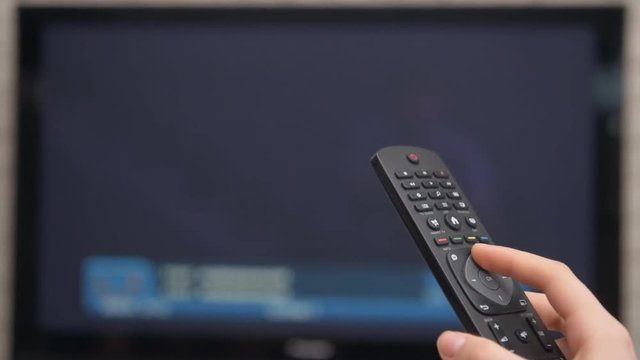 Smart tv and hand pressing remote control.