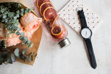 Feminine tabletop, flowers, water with fruits and watch