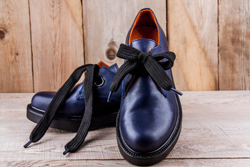 Female leather classic shoes with lacing on the wooden background