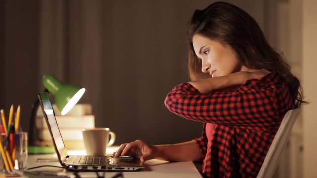 student or woman typing on laptop at night home
