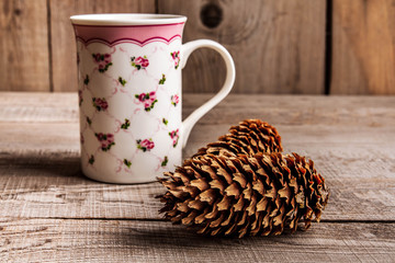 Cup of tea and rustic wooden festive christmas decorations and pine cones on a dark wooden background