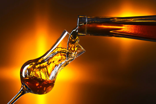 Pouring alcohol into a glass on dark background