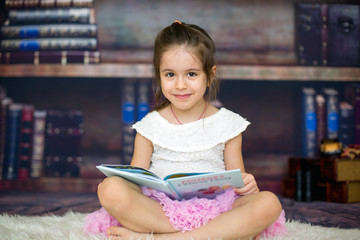Sweet little girl, reading a book at home
