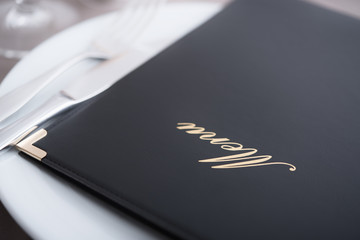 Closeup on menu, arranged table with cutlery and dishes
