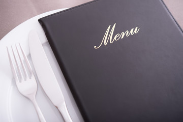 Closeup on menu, arranged table with cutlery and dishes - obrazy, fototapety, plakaty