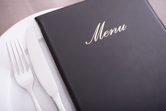 Closeup on menu, arranged table with cutlery and dishes