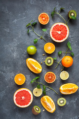 Colorful fresh fruit on dark background. Orange, tangerine, lime, kiwi, grapefruit. Fruit background. Summer food concept. Flat lay, top view