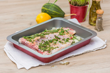 Fish filet in baking tray on wooden table
