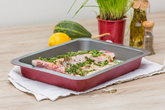 Fish filet in baking tray on wooden table