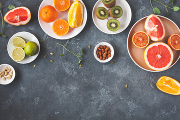 Colorful fresh fruit on dark table. Orange, tangerine, lime, kiwi, grapefruit. Fruit background. Summer food concept. Flat lay, top view, copy space