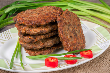liver pancakes or cutlets with chili pepper and green onions on a wooden background