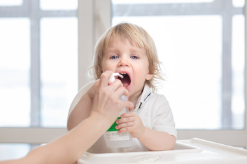 Baby getting medicine through oral spray