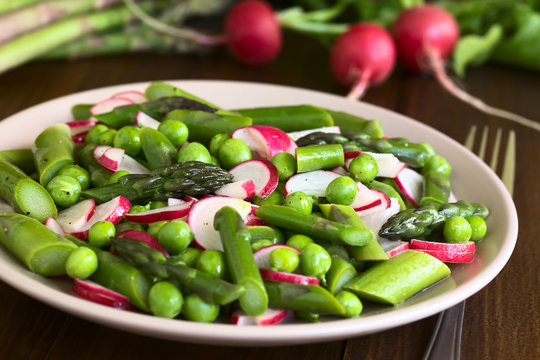 Fresh Green Asparagus, Radish And Pea Salad Served On Plate, Photographed On Dark Wood With Natural Light (Selective Focus, Focus In The Middle Of The Salad)