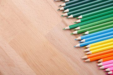 Obraz premium Row of colorful pencils on wooden background