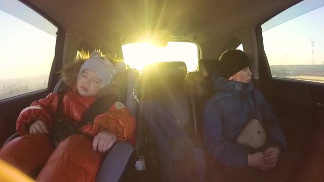 Children riding in the car. The sun's rays through the glass. Slow motion