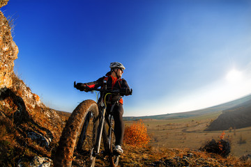 Plakat Cyclist Riding the Bike Down Rocky Hill at Sunset. Close up Extreme Sport Concept. Space for Text.