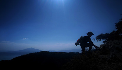 Silhouette of a hiker reaching the summit of a mountain