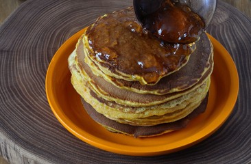 Pumpkin pancakes with orange syrup on the plate.