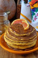 Pumpkin pancakes with orange syrup on the plate.