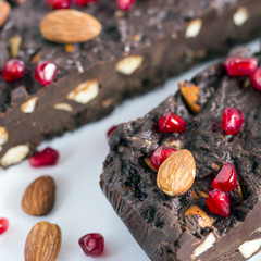 Homemade nut fudge with almond and pomegranate seeds on white background