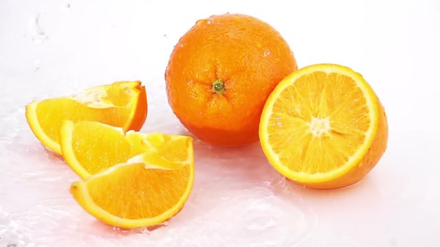 Slices of Orange are Falling on the Table, Splashing Drops. Slow Motion.
