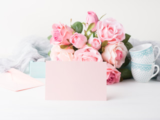 Blank pink paper card for Valentine's or mother woman day. Wedding baby birthday romantic date invitation. Background with roses tray romantic textile and two coffee cups © tenkende