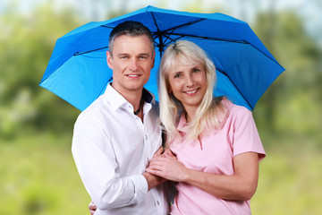 Glückliches älteres Paar unter Regenschirm in der Natur