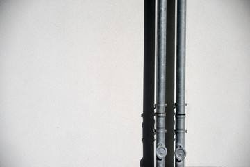 Regenrohr mit Schatten  / Ein Regenrohr wirft einen Schatten auf einer neuen Außenwand aus Putz.